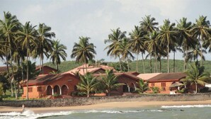 Una propiedad costera con varias edificaciones de ladrillo, palmeras y una playa.