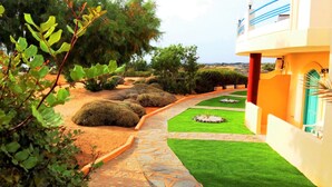 Um jardim bem cuidado com um caminho de pedra, gramados verdes e um edifício com varanda.