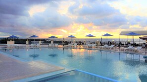 A poolside area with lounge chairs and umbrellas, overlooking the sea during sunset. - Zorbas Beach Village Hotel (Chania)