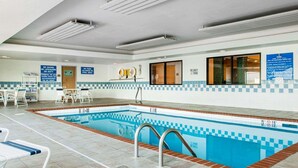 A swimming pool area with a tiled floor, poolside chairs, and a lifeguard stand. - Comfort Inn Goshen (Goshen)