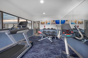 Un gimnasio con cintas de correr, mancuernas y equipamiento de ejercicio.