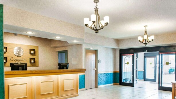 A hotel reception area with a wooden reception desk, a Dell computer, and a sign for 'Comfort Inn'. - Comfort Inn Goshen (Goshen)