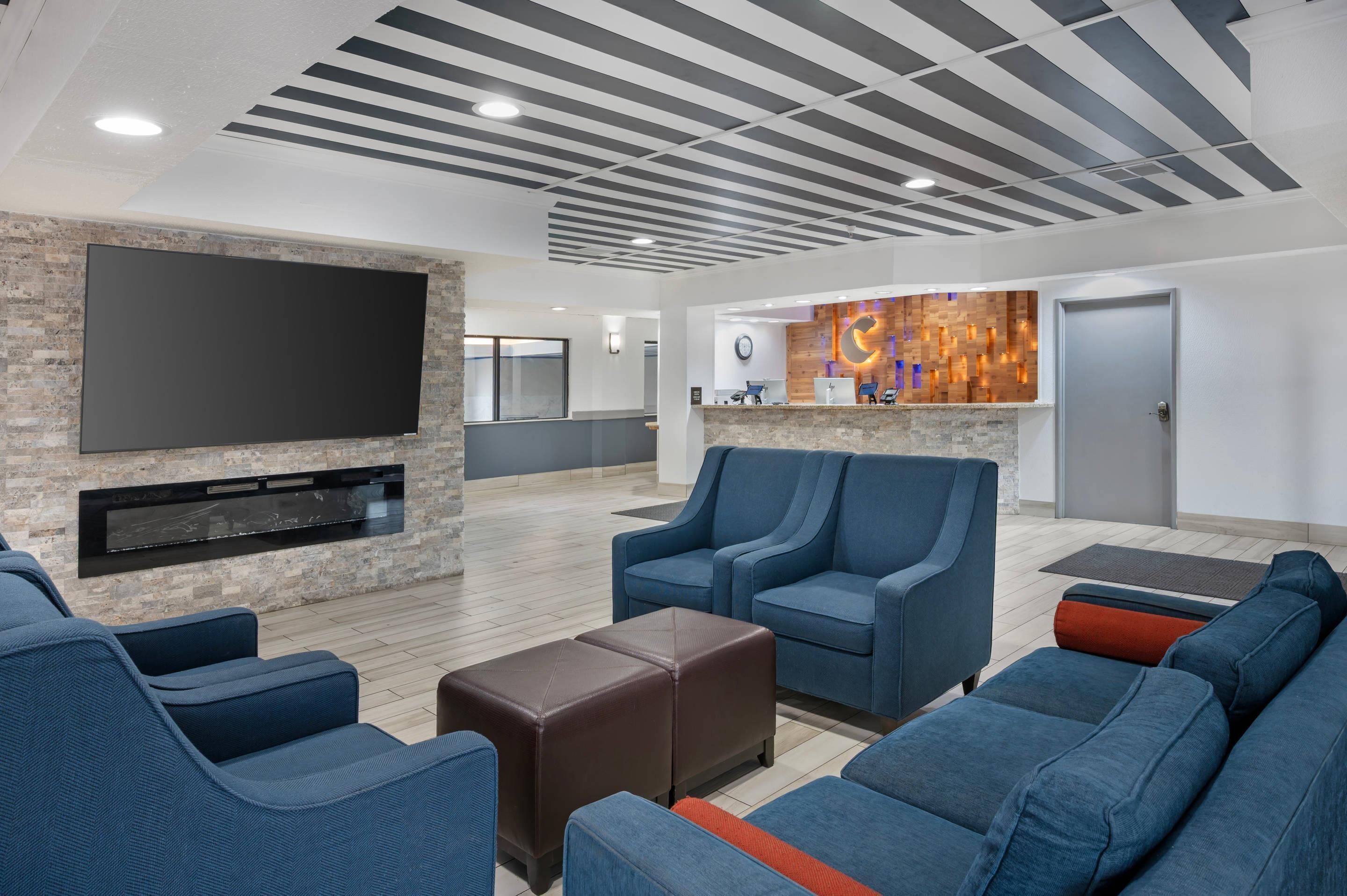 A modern lounge area with a flat-screen TV, seating, and a wooden accent wall.