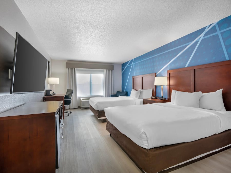 Habitación de hotel con una cama grande, un escritorio, un televisor y una ventana con cortinas.