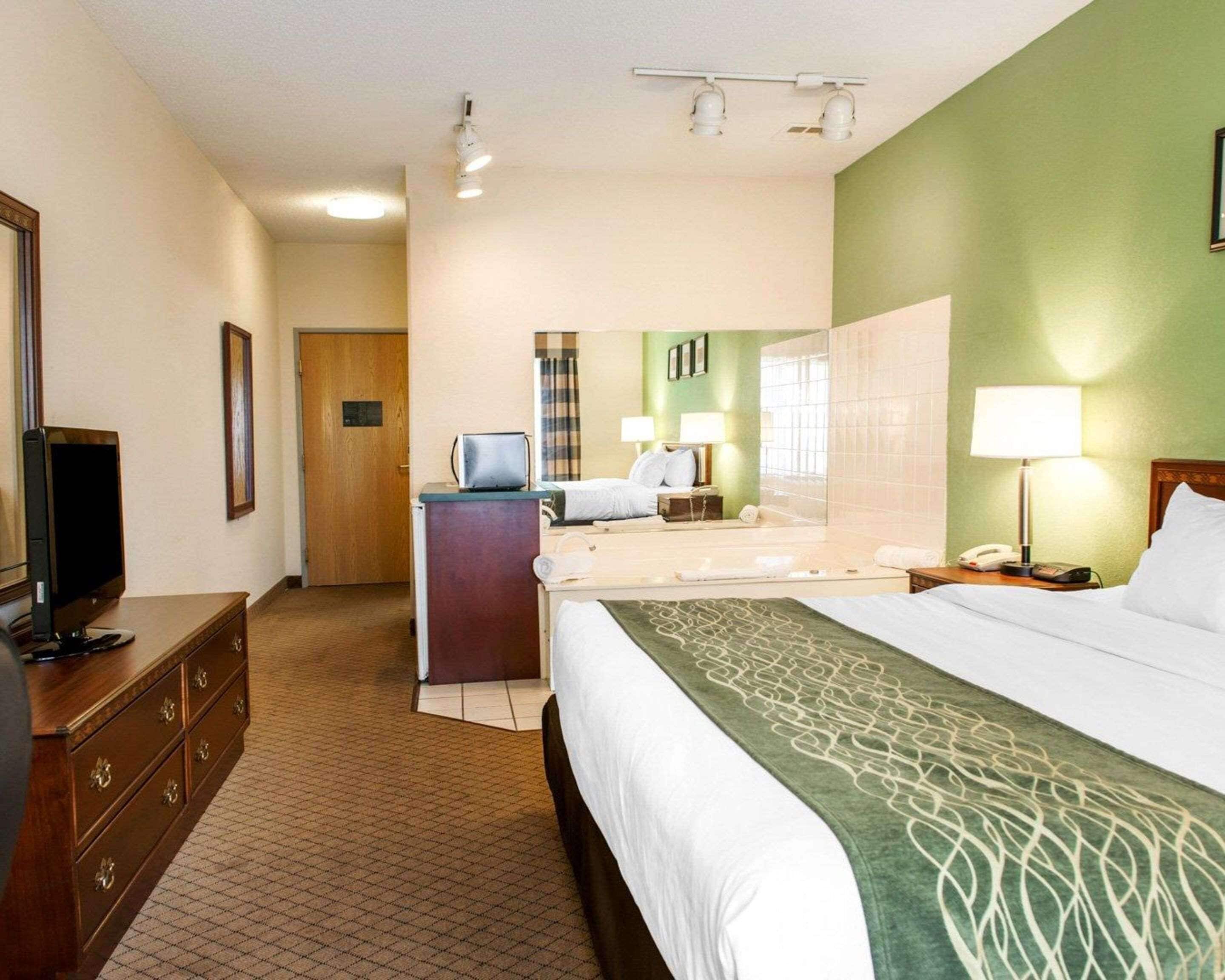 A hotel room with a bed, a desk with a computer, a television, and a mirror.