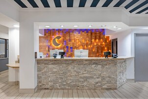Una recepción con pared de madera, diseño en forma de luna creciente y dos monitores de ordenador.