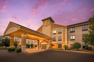 Un hotel con entrada cubierta, varios pisos y cielo despejado.