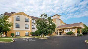 A hotel with a parking lot, a covered entrance, and a clear sky.