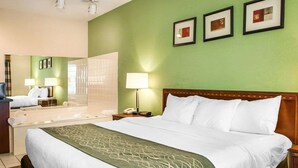 A hotel room with a large bed, a desk with a chair, a mirror, and a green wall with framed pictures. - Comfort Inn Goshen (Goshen)