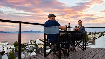Una pareja sentada en una mesa con una vista panorámica de un cuerpo de agua y edificios al fondo.