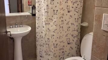 Un baño con un lavamanos pedestal blanco, un inodoro y una cortina de ducha con estampados de animales.