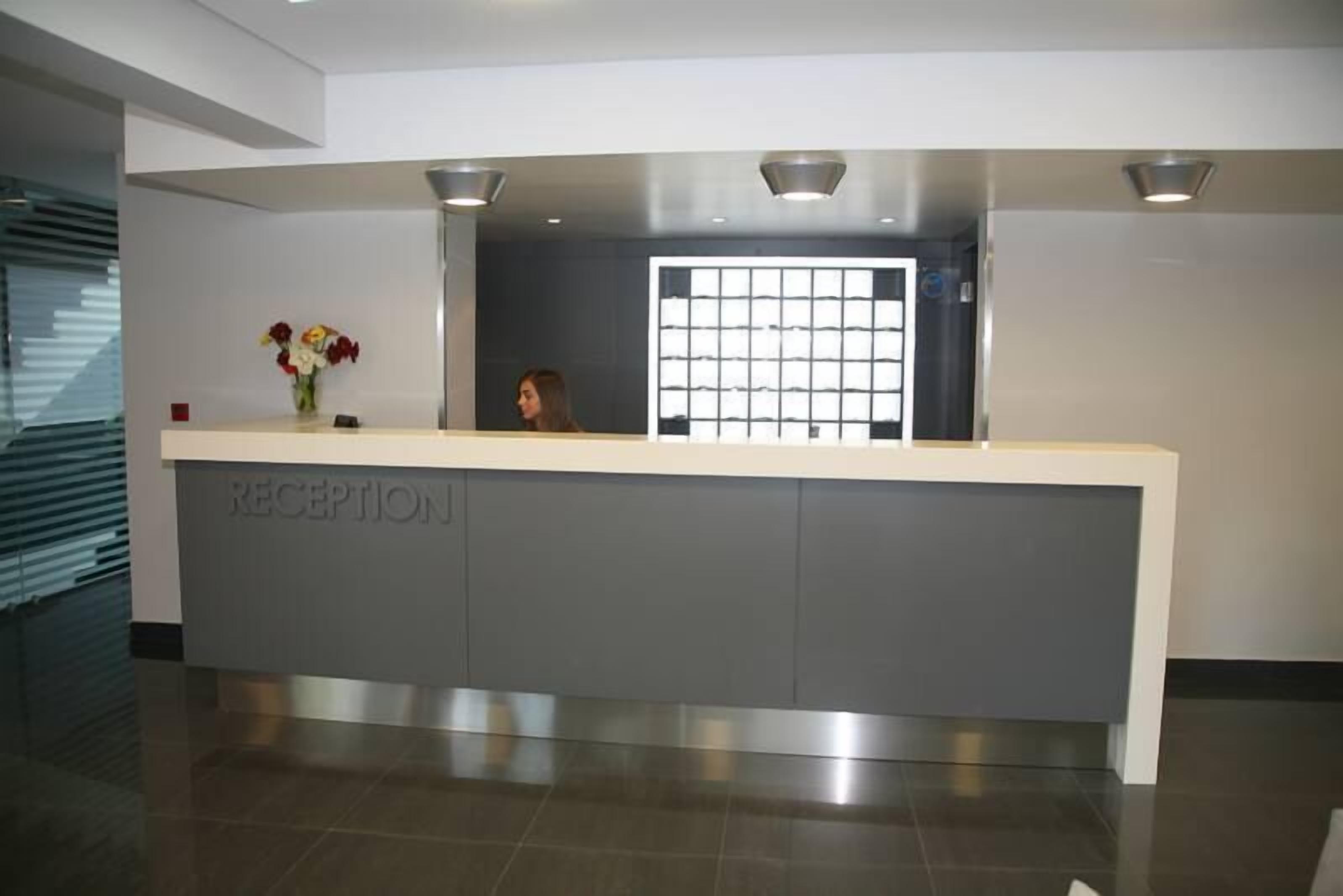 Un mostrador de recepción de diseño moderno, una puerta de cristal y un florero con flores.