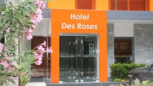 A hotel entrance with a prominent orange sign reading "Hotel Des Roses." - Hotel Des Roses (Kifisia)
