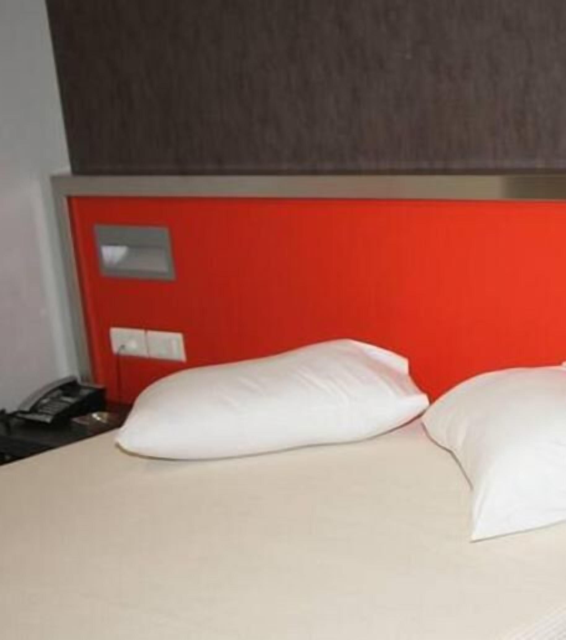 A bed with two white pillows and a red headboard.