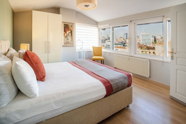 A bedroom with a large bed, a chair, a radiator, and a window with a city view. - Cheya Tesvikiye (Istanbul)