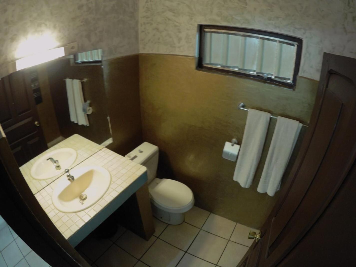Une salle de bain avec deux lavabos, des toilettes, un miroir et un porte-serviettes.