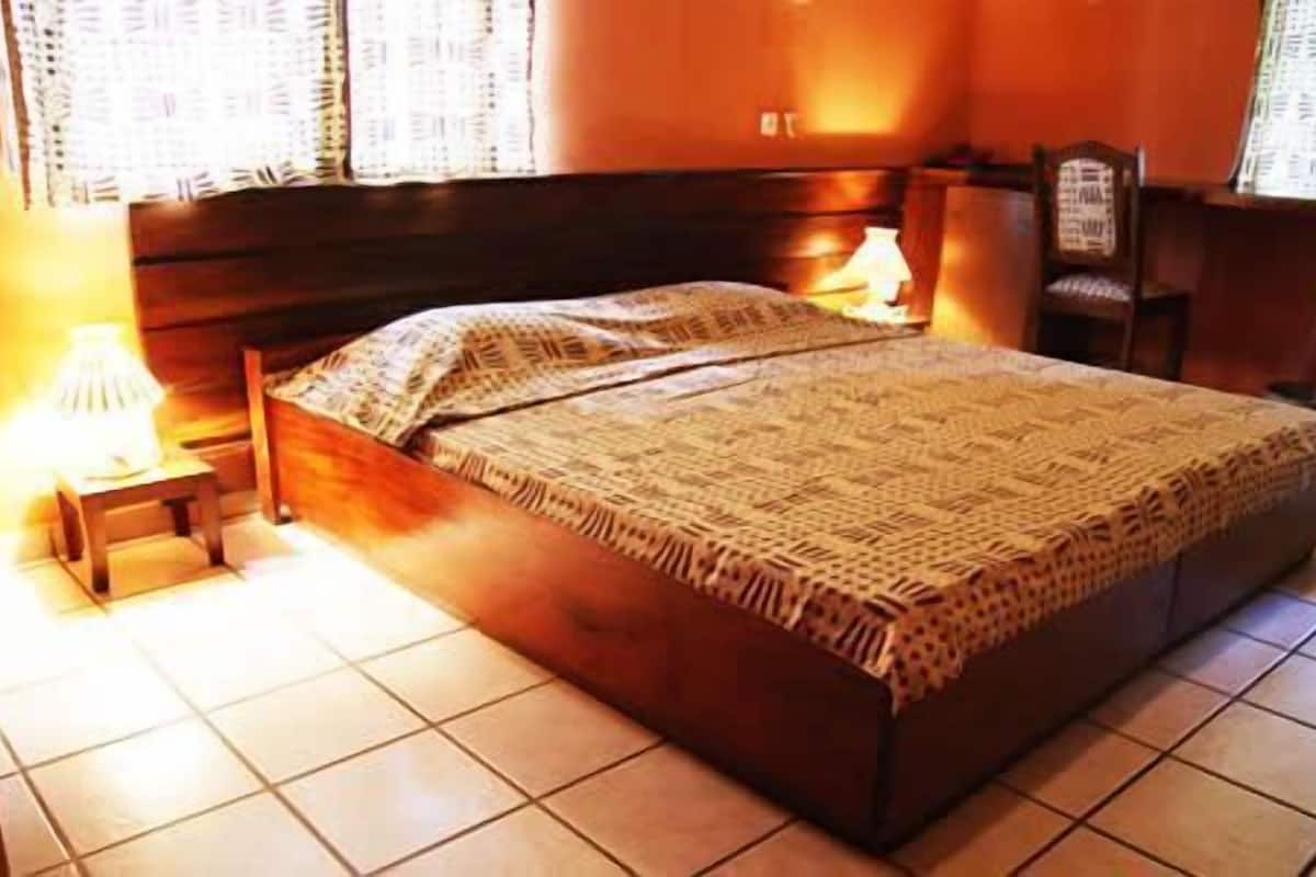 Quarto com cama de madeira, mesa de cabeceira e duas luminárias.