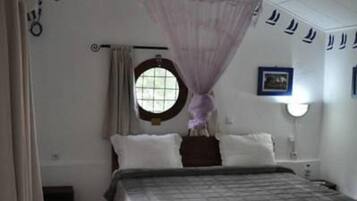 Una camera da letto con un letto, una finestra, un comodino e un lampadario.