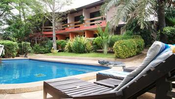 Relax by the serene pool surrounded by lush gardens and a palm tree.