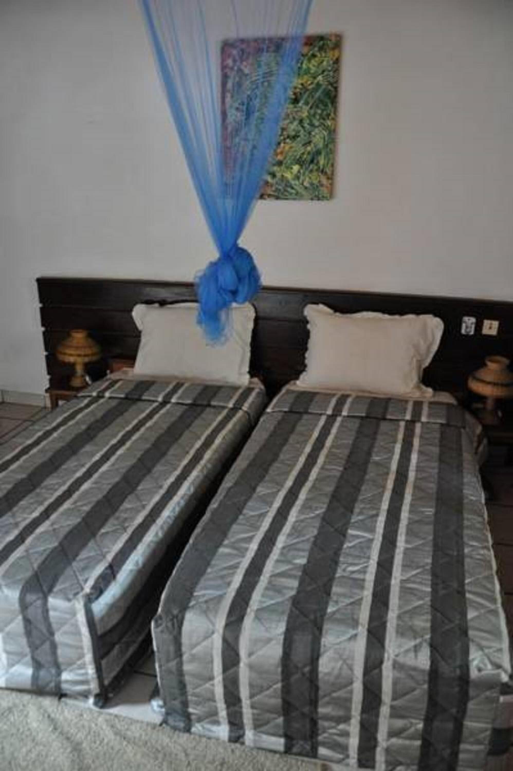 A double bed with striped bedding and a blue canopy.