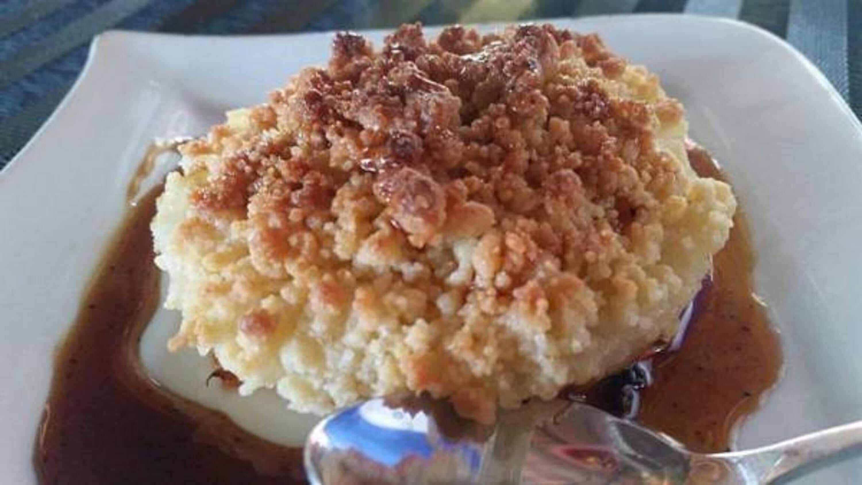 A dessert with a crumbly topping and syrup on a white plate.
