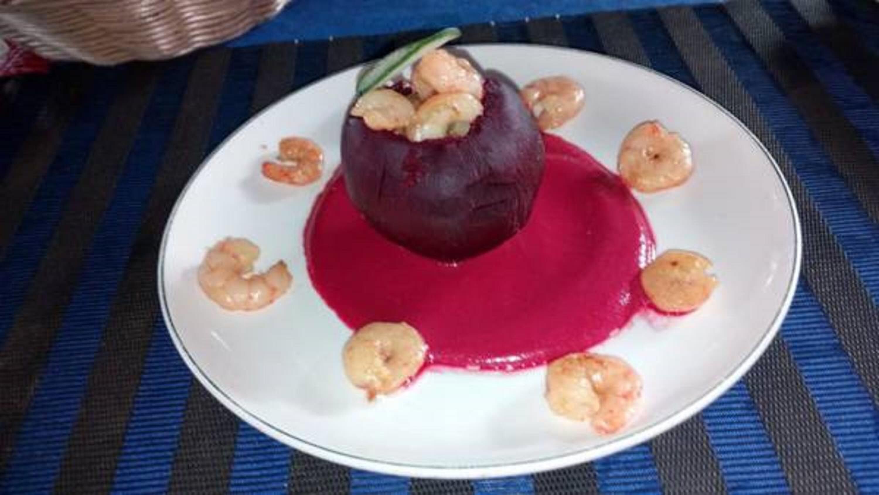 Un plato con un guiso de remolacha, camarones y salsa roja.