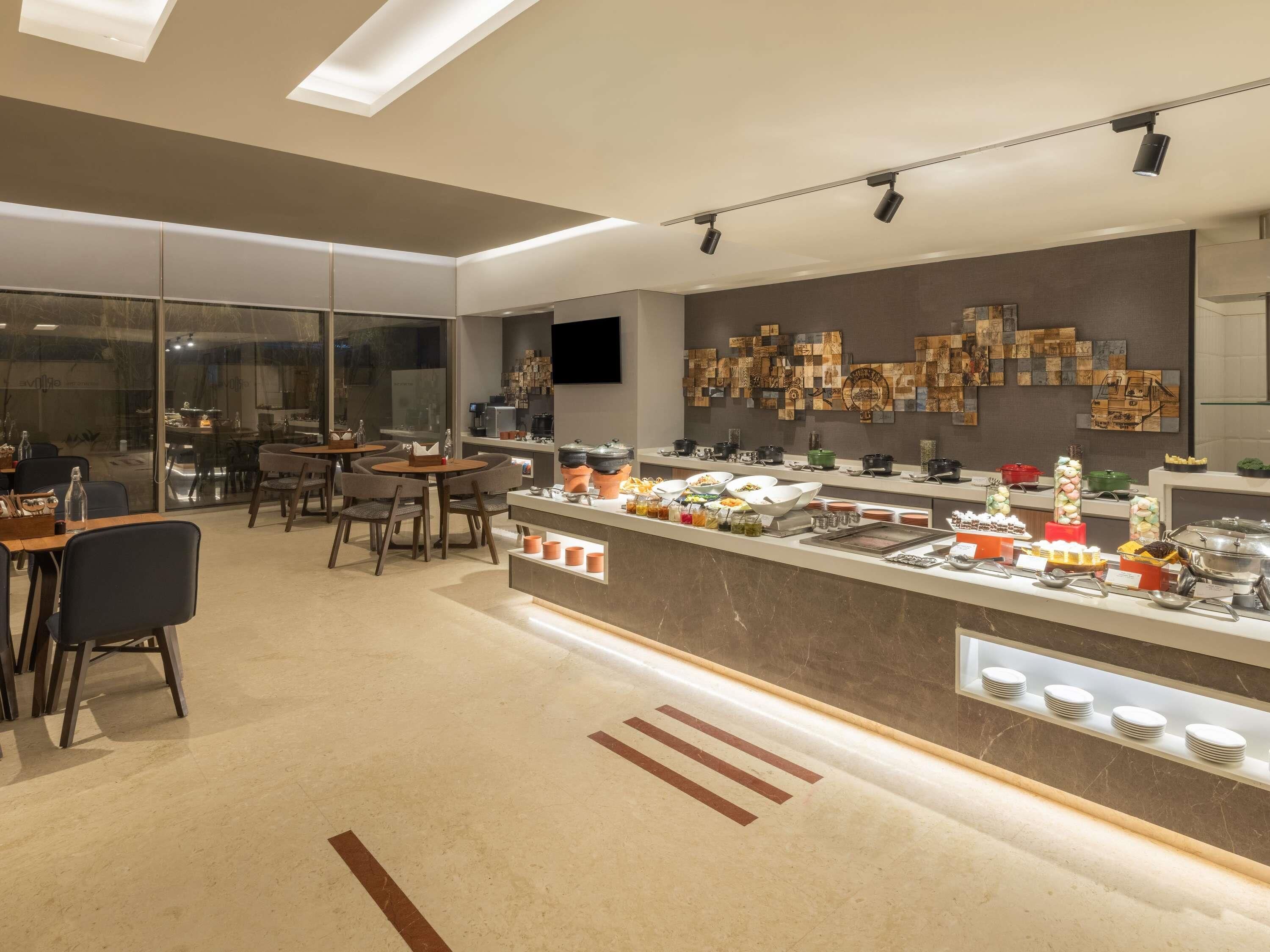 A modern restaurant with a buffet bar, seating area, and a wall with decorative tiles.
