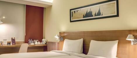 Habitación de hotel con una cama grande, un escritorio con silla, una zona de café y un cuadro en la pared.