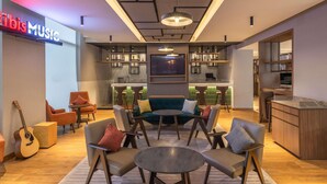 A modern lounge area with a bar, seating arrangements, and a visible sign reading "Tibis Music". - ibis Mumbai Airport Hotel (Mumbai)