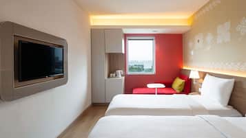 Una habitación de hotel con una cama, un televisor montado en la pared, una mesita y una ventana con vistas a la ciudad.