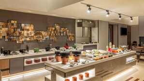 A modern kitchen with a central island, various cooking utensils, and a wall decorated with patterned tiles. - ibis Mumbai Airport Hotel (Mumbai)