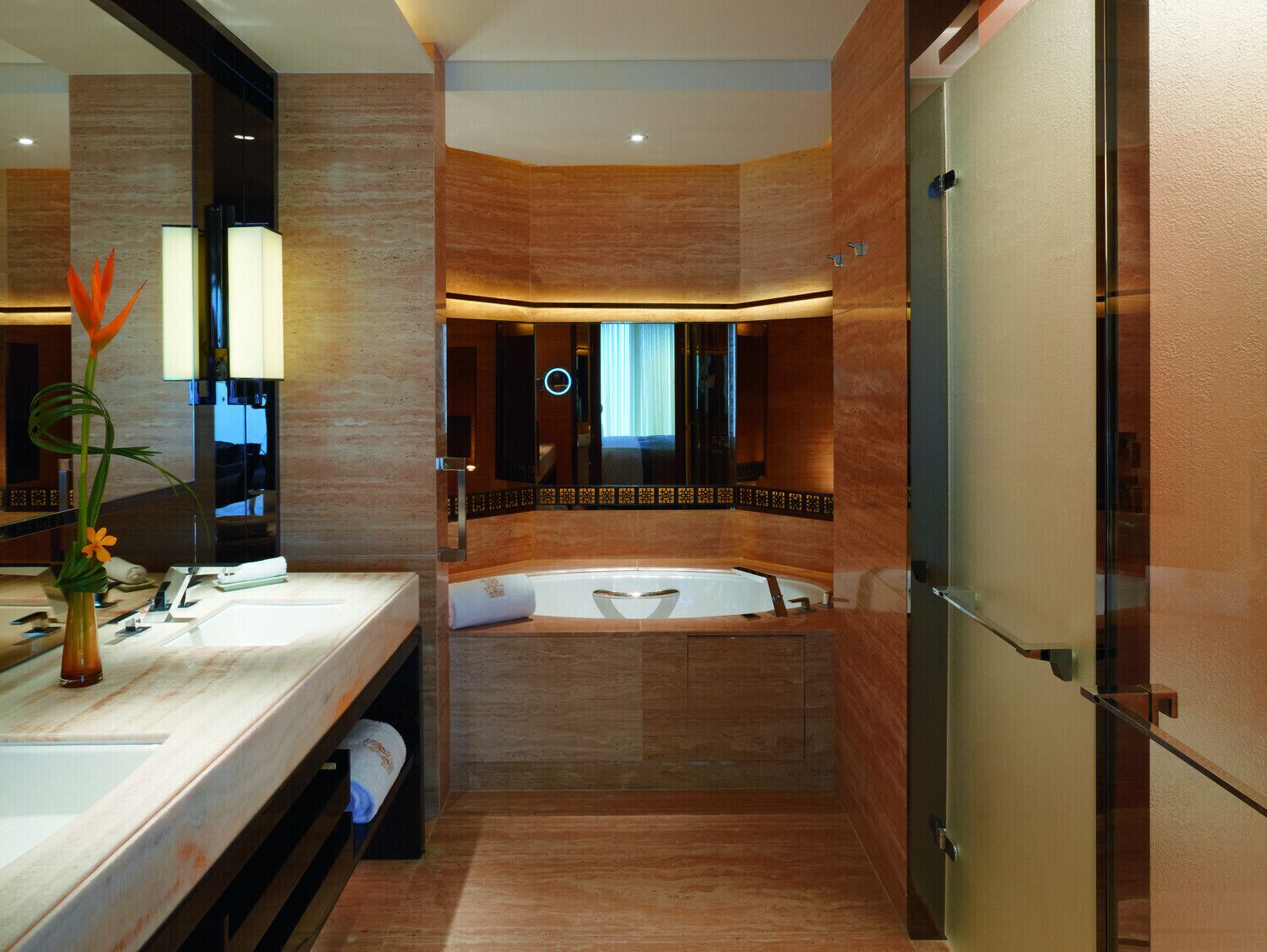 A modern bathroom with a large bathtub, a vanity with a mirror, and a decorative plant.