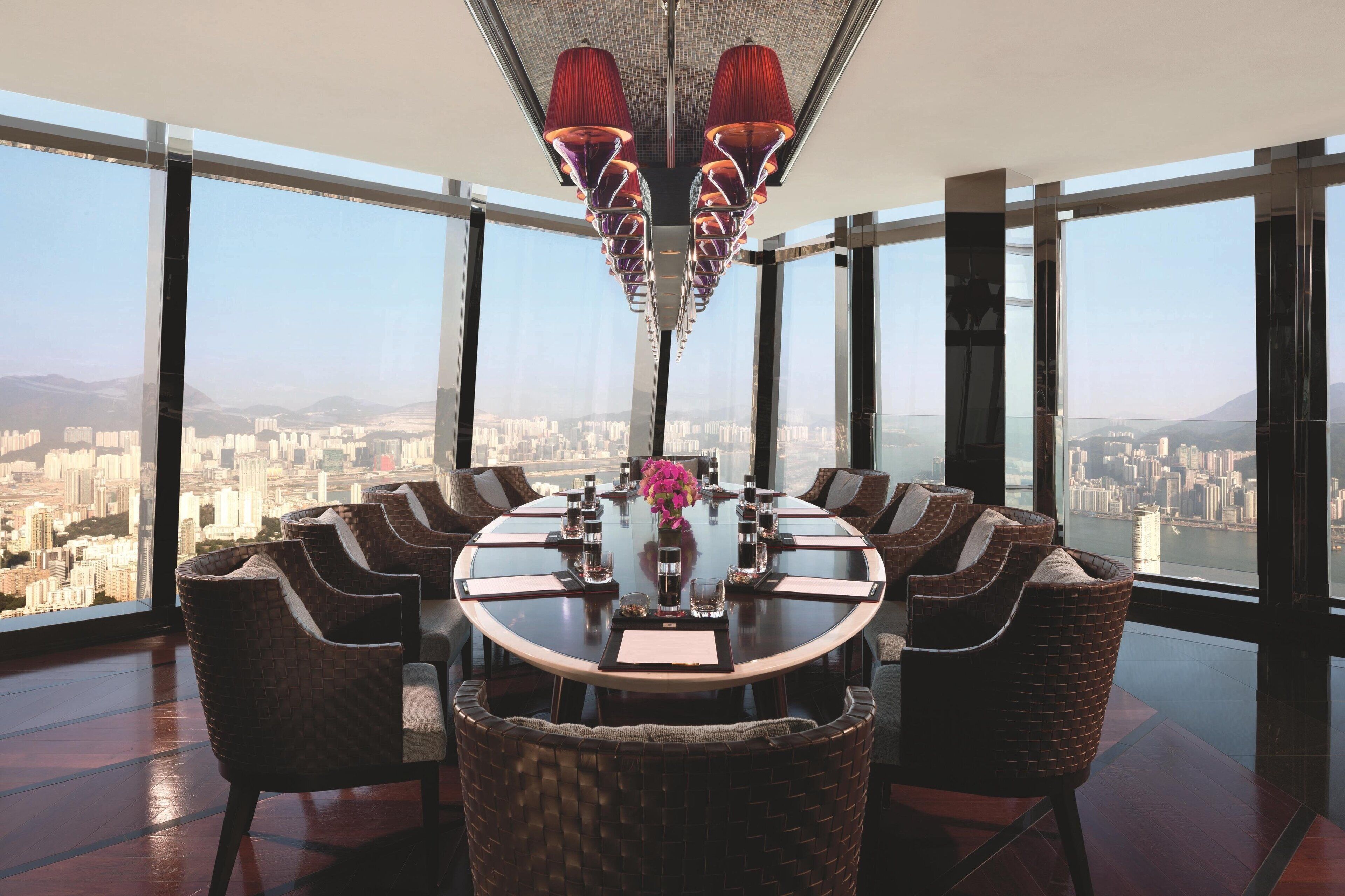 A high-rise dining area with a panoramic city view, a round table, and wicker chairs.