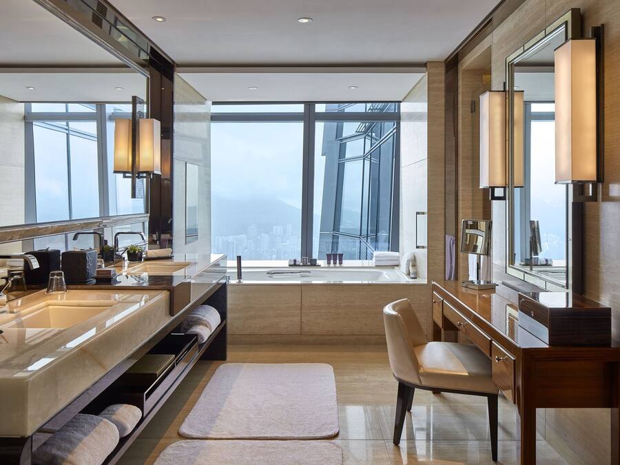 A modern bathroom with dual sinks, a large mirror, and a view of a cityscape.