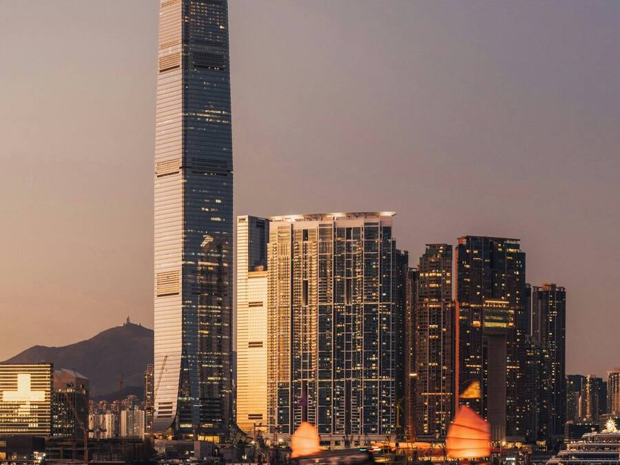 A city skyline with modern high-rise buildings, a body of water, and a yellow buoy.