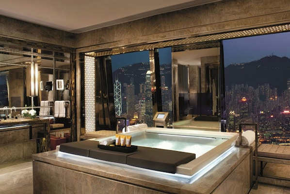 A high-rise hotel room with a cityscape view, a spa area, and a modern bathroom.