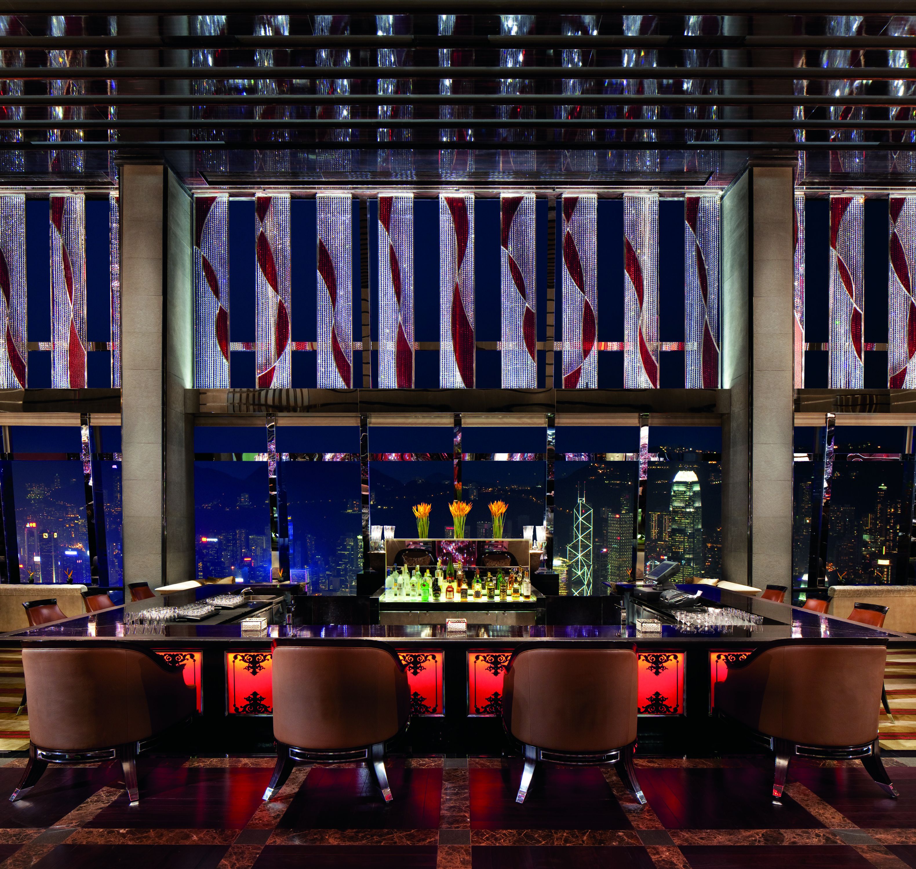 Espaço de bar com vista para a cidade, balcão, assentos e detalhes decorativos.