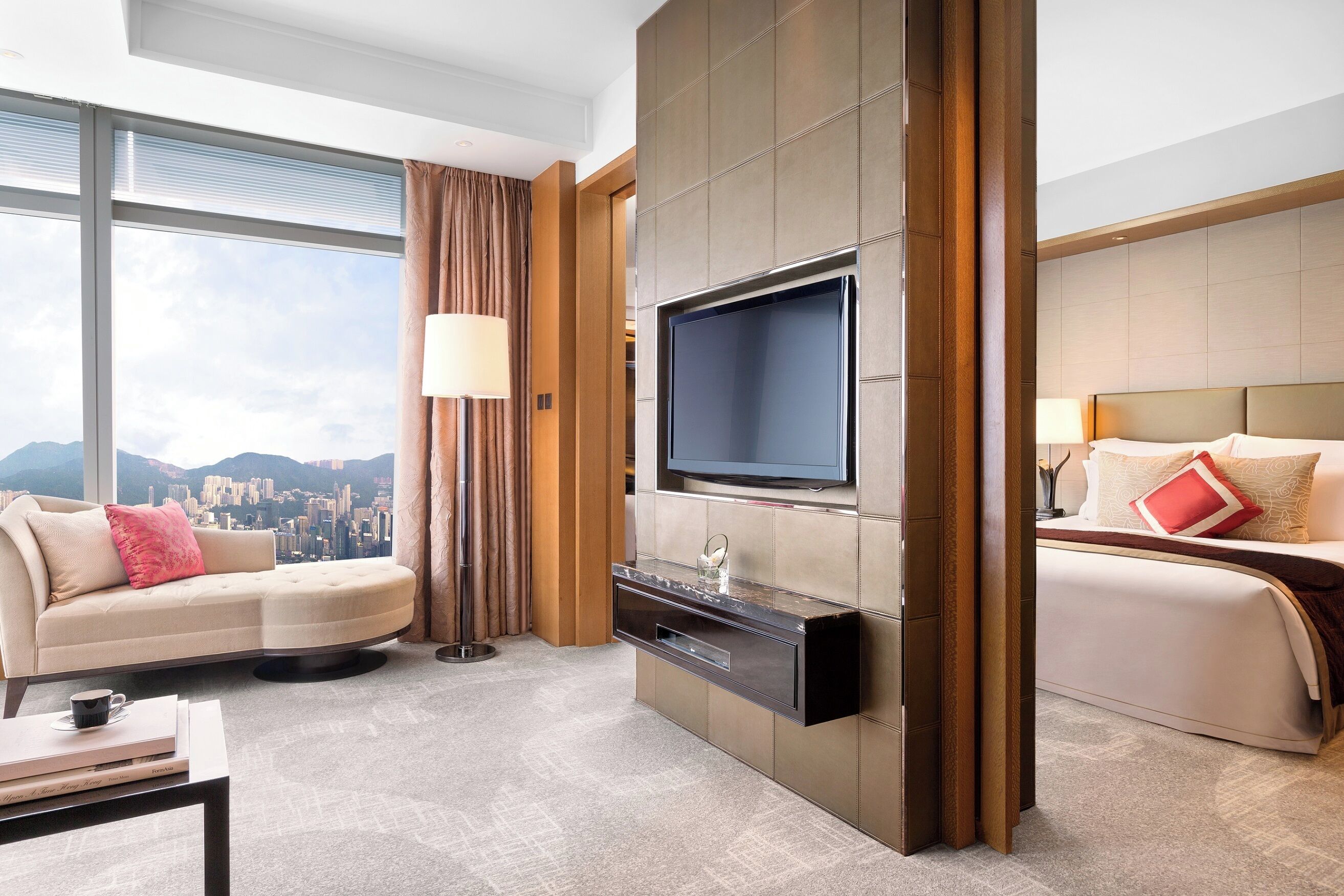 Una camera d'albergo moderna con una grande televisione, un divano, un letto e vista sulla città.