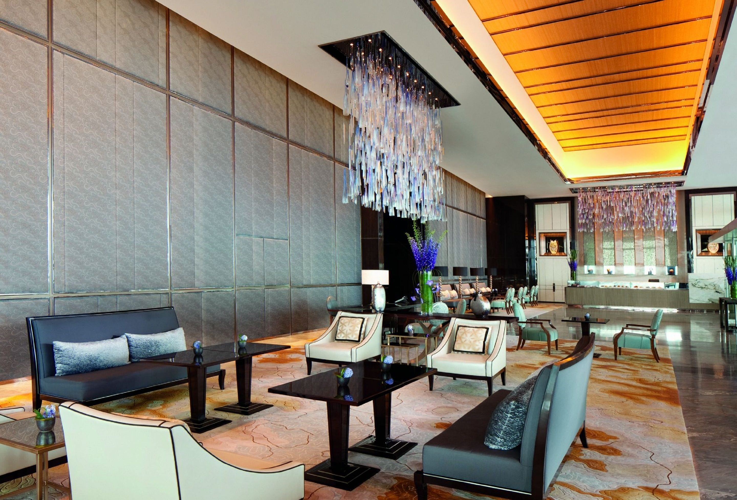 A spacious lobby with a modern design, featuring sofas, armchairs, and a reception desk.
