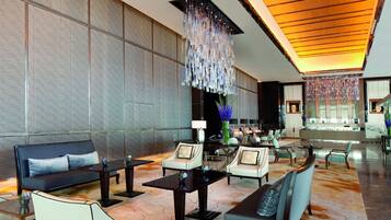 A spacious lobby with a modern design, featuring sofas, armchairs, and a reception desk.