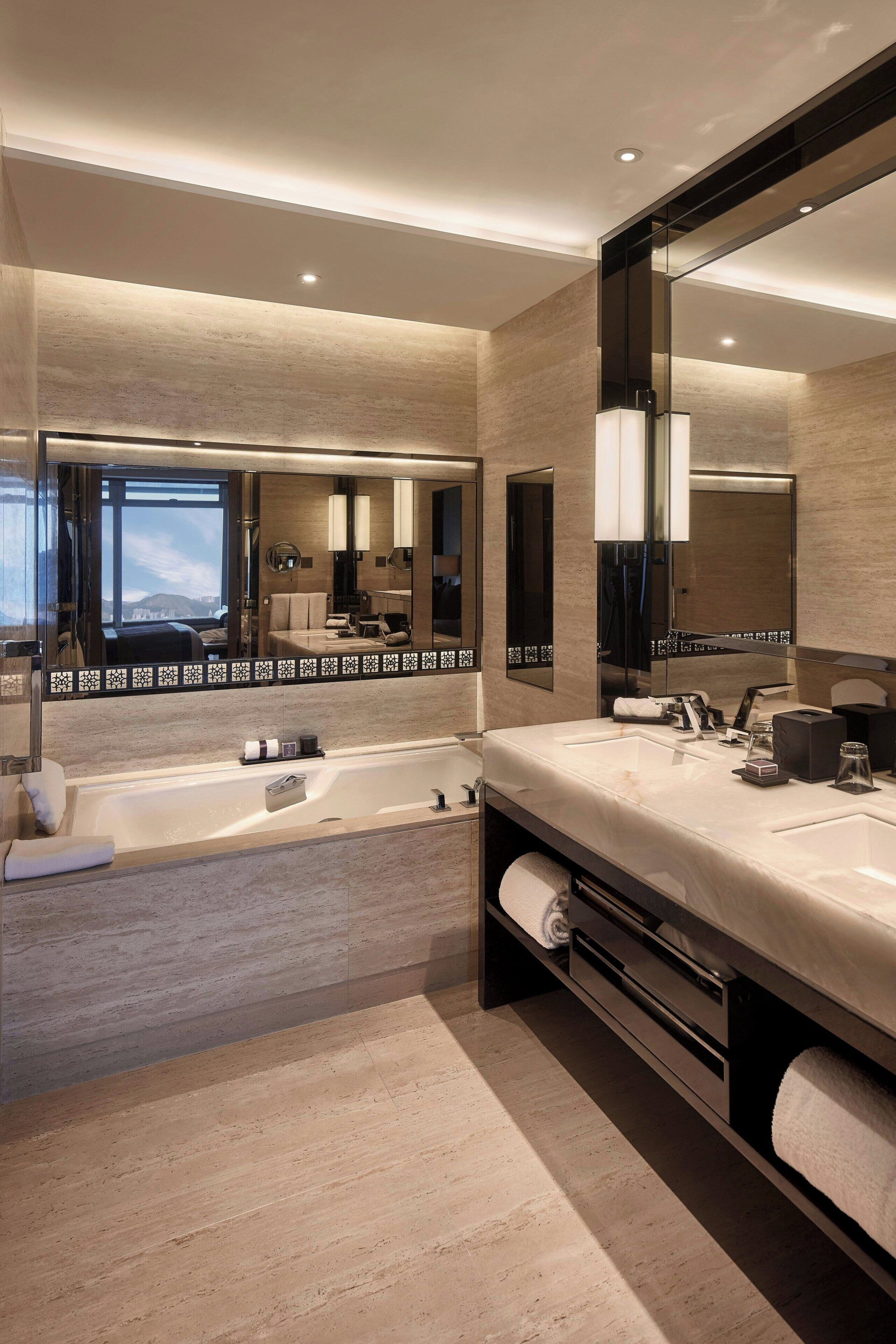 Une salle de bain moderne avec un grand miroir, une baignoire et un meuble-lavabo.