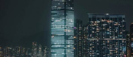 A high-rise building with illuminated windows and a prominent 'M+' sign at its base.