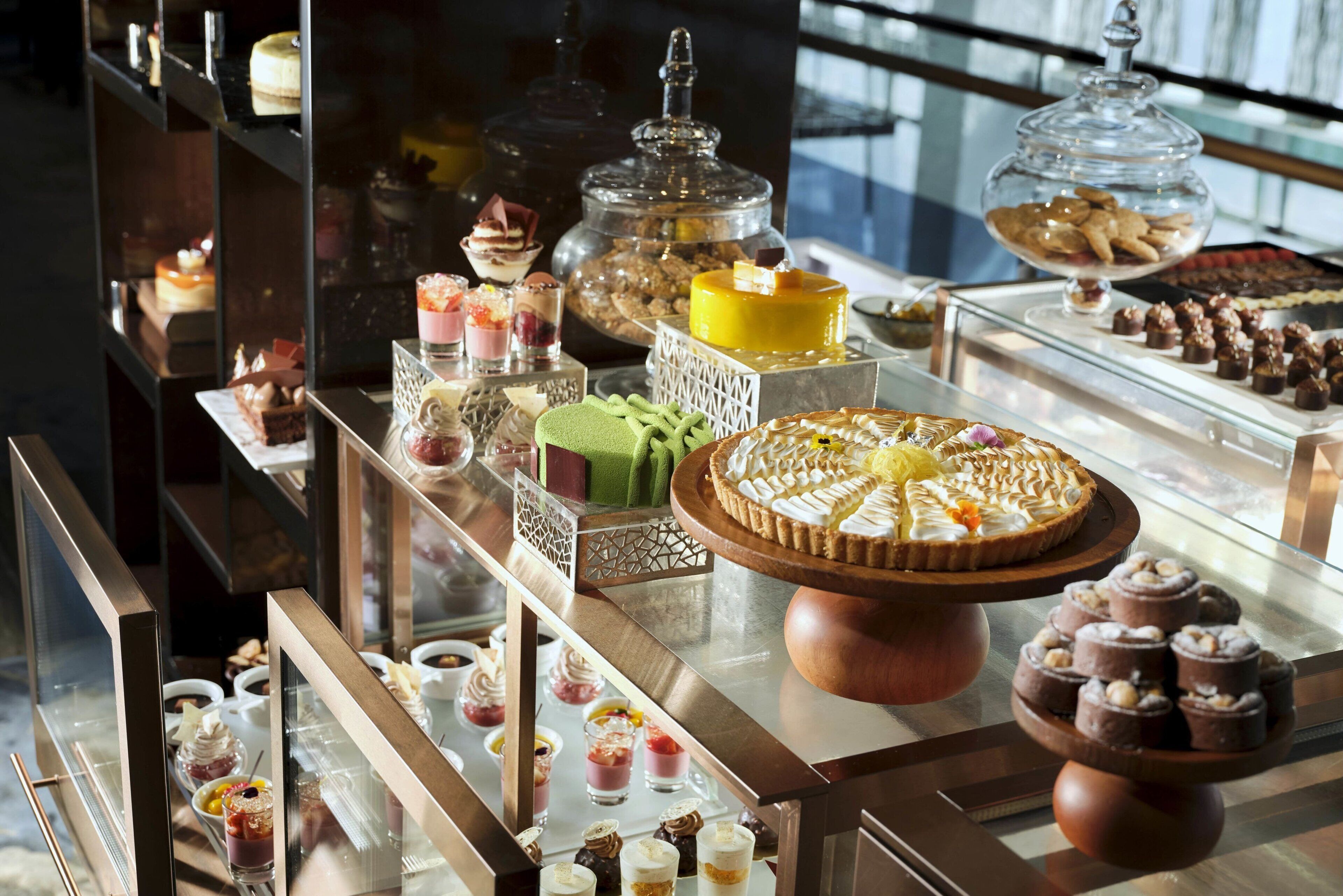 Una variedad de postres expuestos en una vitrina, incluyendo pasteles, hojaldres y otras delicias dulces.