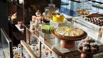 Una variedad de postres expuestos en una vitrina, incluyendo pasteles, hojaldres y otras delicias dulces.