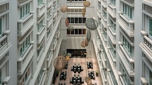 A multi-story hotel atrium with a glass ceiling, multiple floors, and hanging spherical light fixtures.