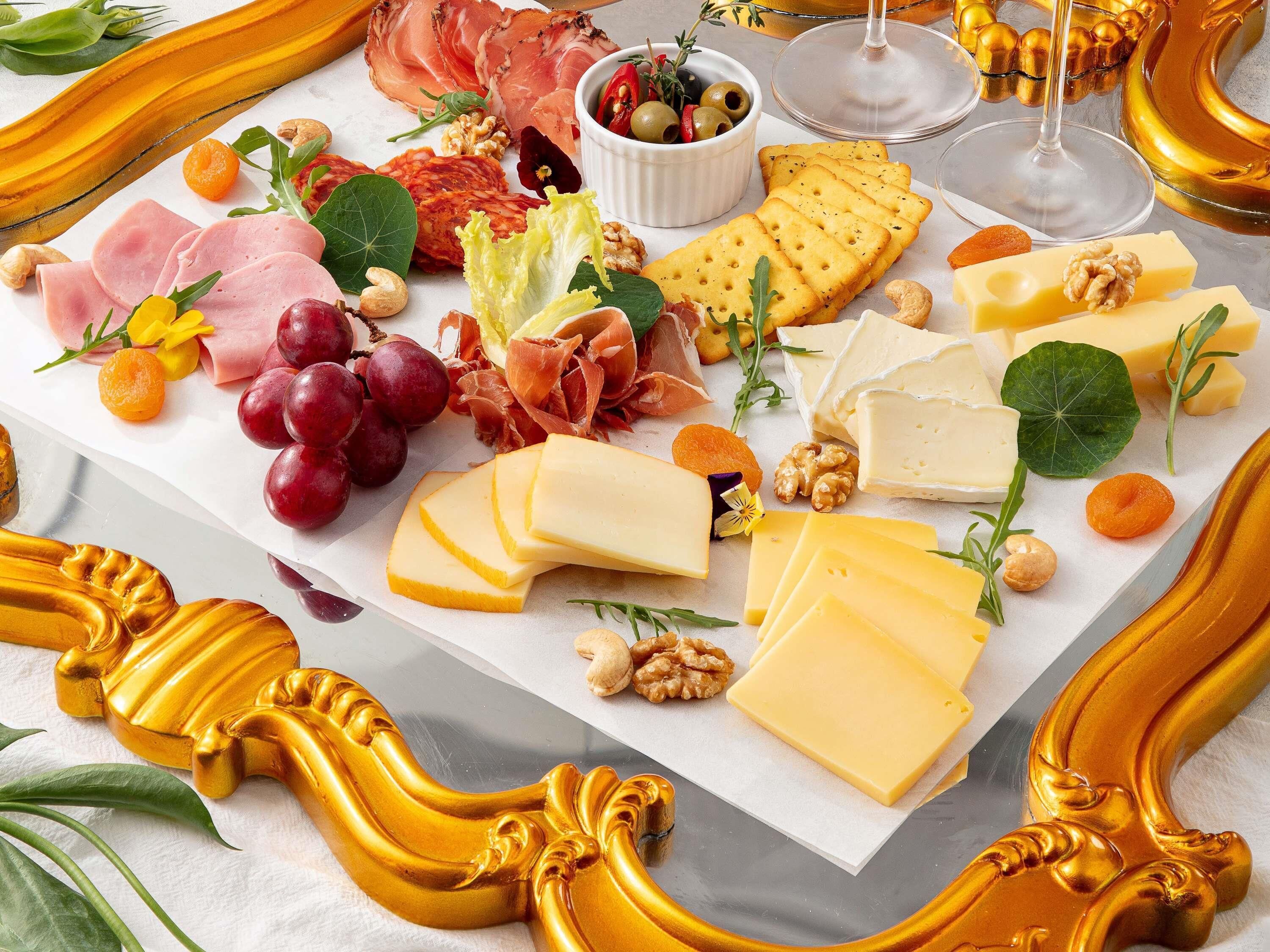 A charcuterie board with various cheeses, meats, fruits, and nuts.