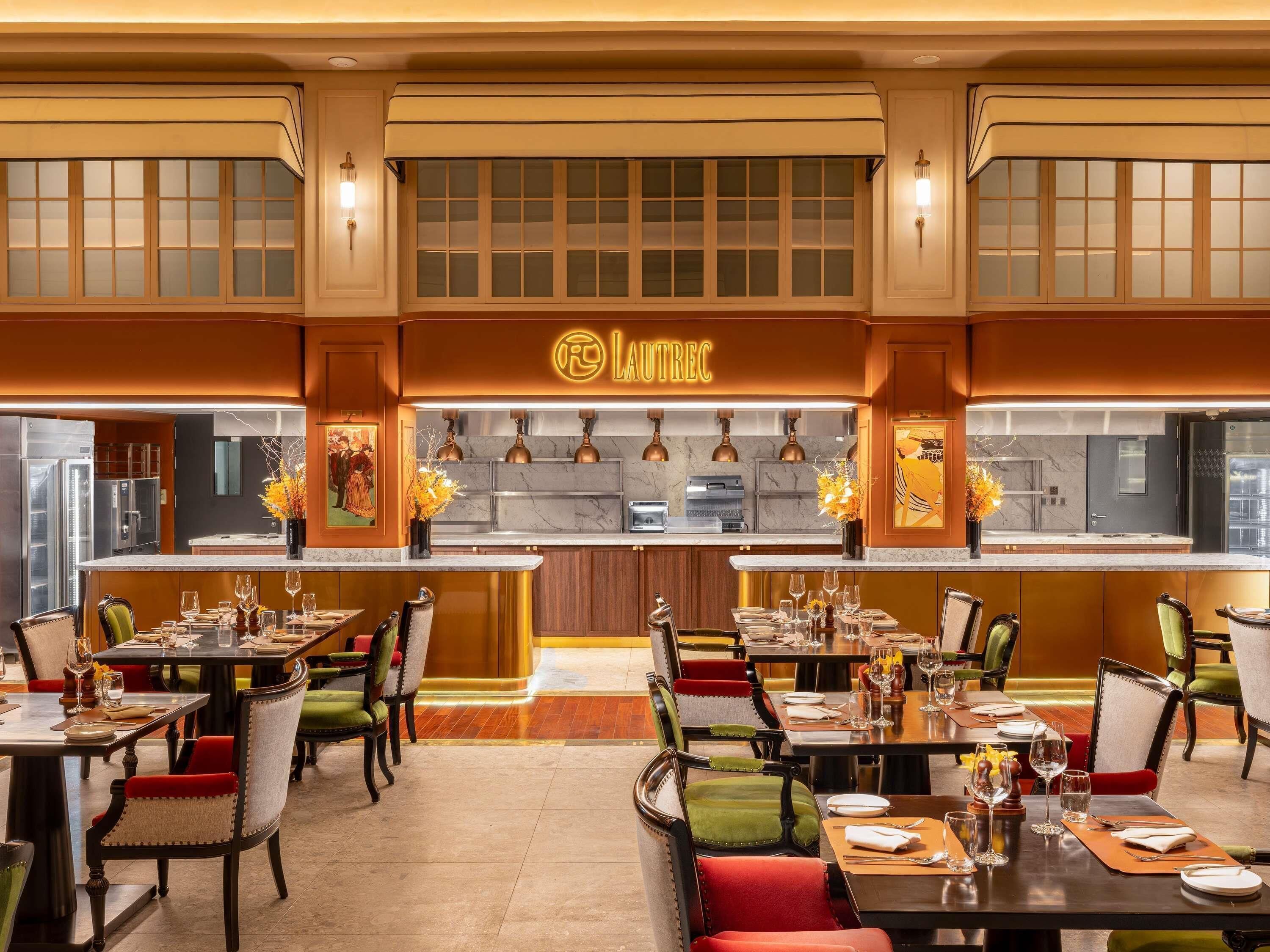 Un restaurante con un interior cálido, una zona de bar central y varias mesas con sillas.