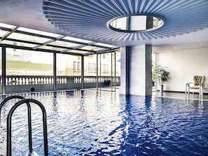 Una piscina techada, sillones reclinables de piscina