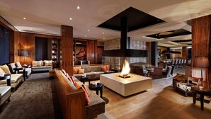Un vestíbulo amplio con chimenea central, zonas de estar y un bar.