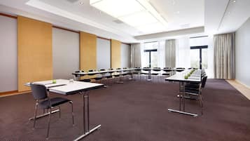 A conference room with a long table, chairs, and a carpeted floor.